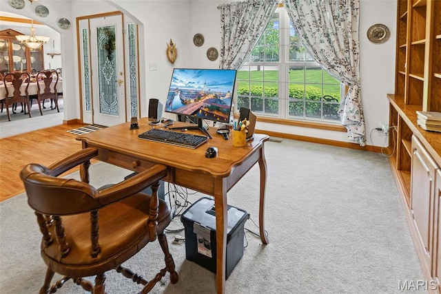 office area featuring arched walkways, a chandelier, baseboards, and carpet floors