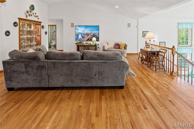 living room featuring light wood-type flooring, lofted ceiling, and baseboards
