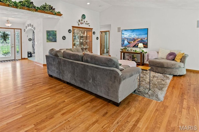 living area with light wood finished floors, lofted ceiling, and baseboards