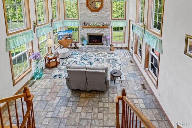 living area featuring baseboards, a brick fireplace, and stone finish floors