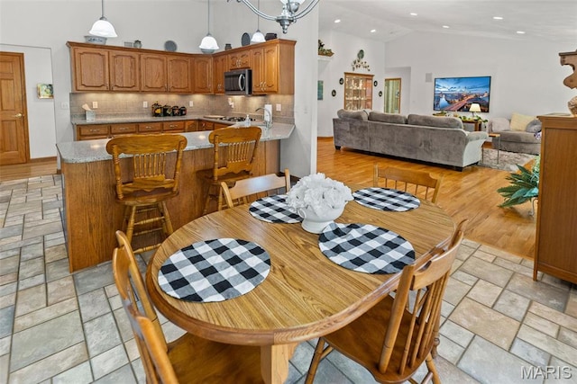 dining area with high vaulted ceiling, stone tile flooring, and recessed lighting