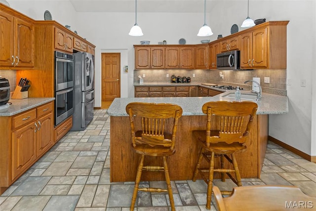 kitchen with stainless steel appliances, stone tile flooring, a sink, tasteful backsplash, and light stone countertops
