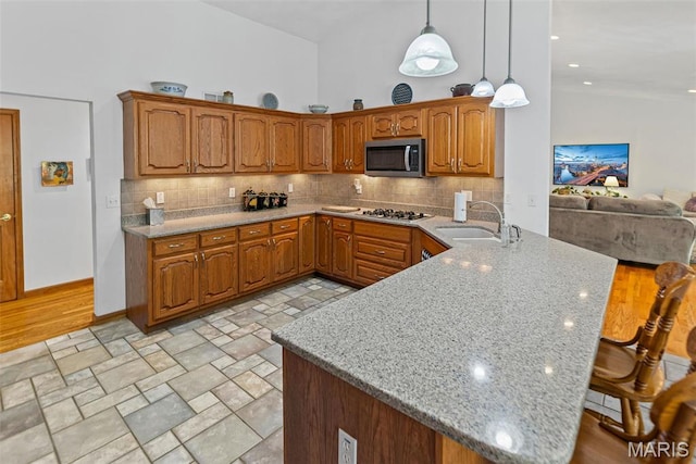 kitchen featuring appliances with stainless steel finishes, a peninsula, a sink, and decorative backsplash