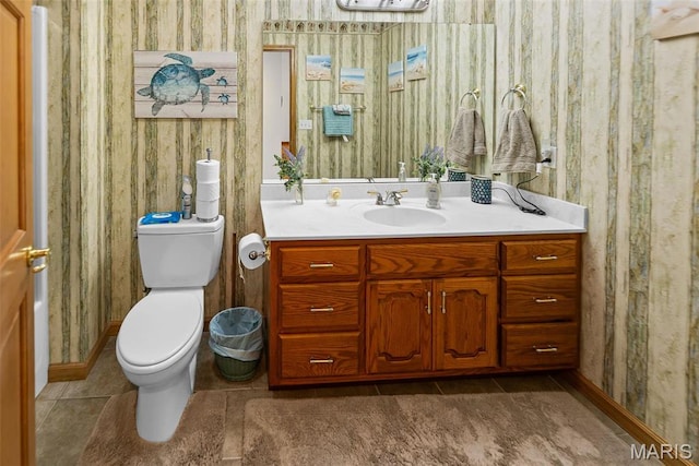 half bath with wallpapered walls, toilet, vanity, tile patterned floors, and baseboards