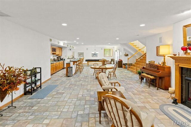 living room featuring a fireplace, stairs, recessed lighting, stone tile flooring, and baseboards