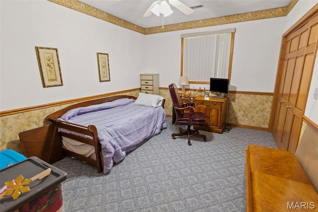 bedroom with a wainscoted wall, carpet, and a ceiling fan