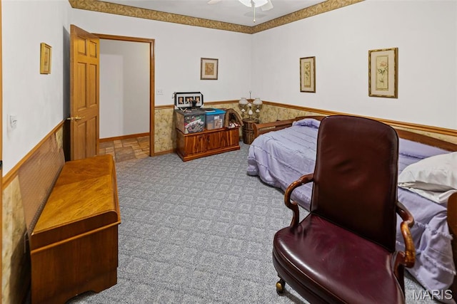 carpeted bedroom featuring a wainscoted wall and ceiling fan