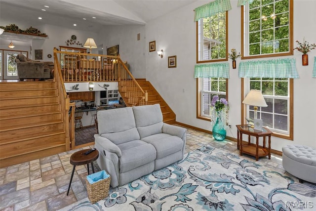 living room featuring stairs, baseboards, recessed lighting, stone finish flooring, and vaulted ceiling