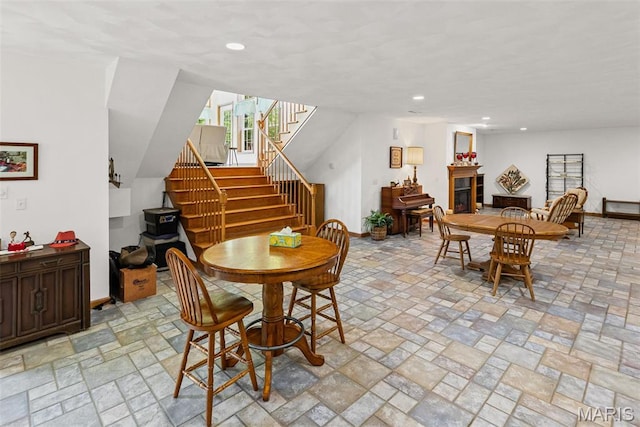 dining area with stairway, a fireplace, baseboards, recessed lighting, and light stone finish flooring