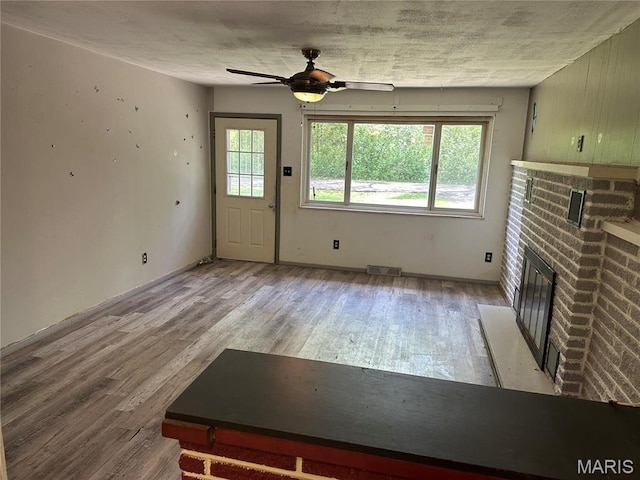 2145 Freckles Dr, High Ridge, MO 63049 - unfurnished living room with wood finished floors, ceiling fan, and a brick fireplace