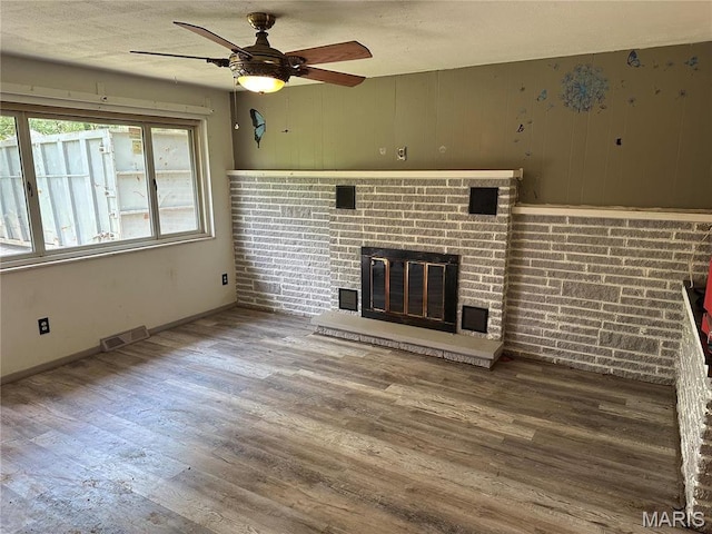 2145 Freckles Dr, High Ridge, MO 63049 - unfurnished living room with wood finished floors, ceiling fan, a fireplace, baseboards, and a textured ceiling