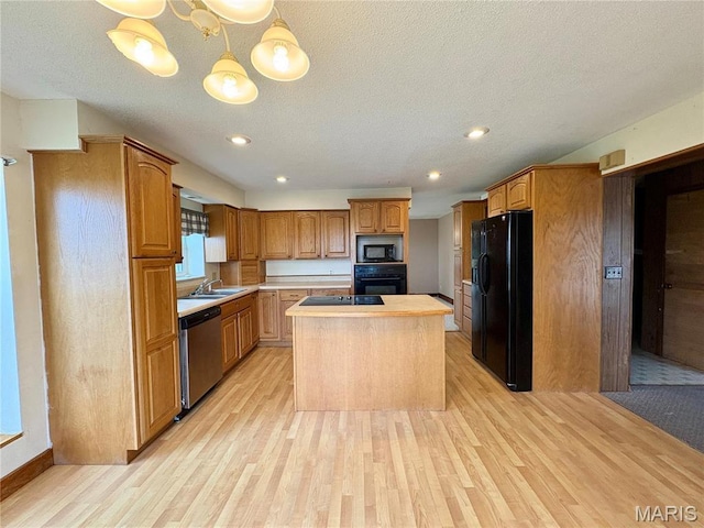 9621 Main St, Altenburg, MO 63732 - kitchen with black appliances, a sink, light wood finished floors, a kitchen island, and light countertops