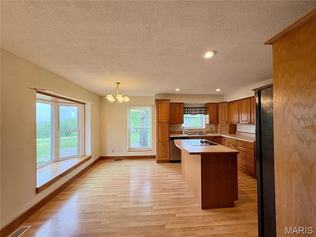9621 Main St, Altenburg, MO 63732 - kitchen featuring a textured ceiling, light wood finished floors, brown cabinets, light countertops, and a chandelier