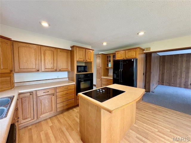 9621 Main St, Altenburg, MO 63732 - kitchen with black appliances, light wood-style floors, a kitchen island, brown cabinetry, and a textured ceiling