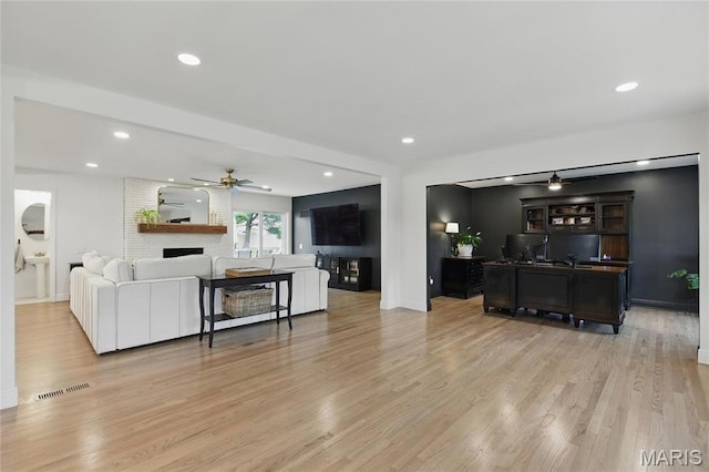 living area featuring ceiling fan, light wood-type flooring, a fireplace, baseboards, and recessed lighting