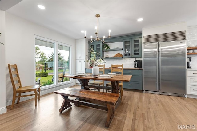 dining area featuring healthy amount of natural light, light wood-type flooring, recessed lighting, and a chandelier
