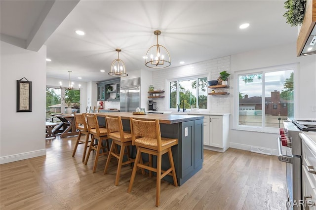 kitchen featuring open shelves, high quality appliances, a chandelier, a kitchen bar, and backsplash