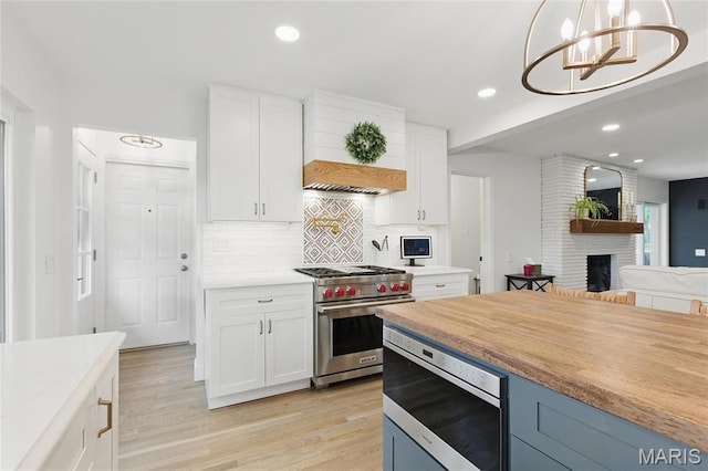 kitchen with appliances with stainless steel finishes, custom exhaust hood, tasteful backsplash, open floor plan, and white cabinets