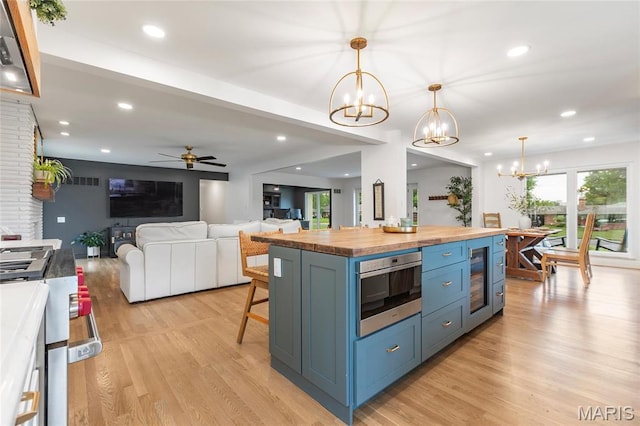 kitchen with wooden counters, a chandelier, light wood-type flooring, beverage cooler, and recessed lighting