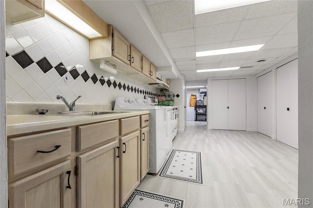 kitchen featuring washer and clothes dryer, light brown cabinetry, a sink, light countertops, and a paneled ceiling