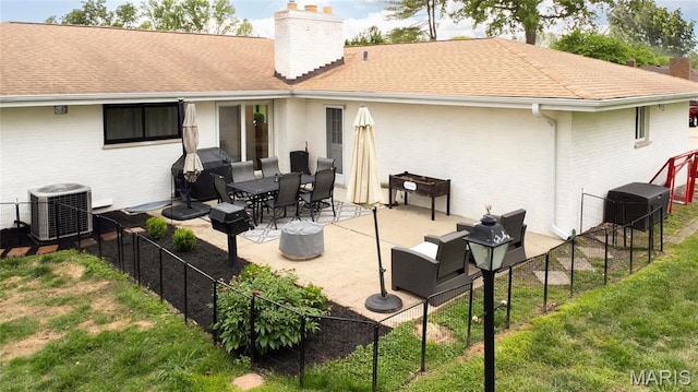 rear view of property with a chimney, central AC, a patio, brick siding, and a shingled roof