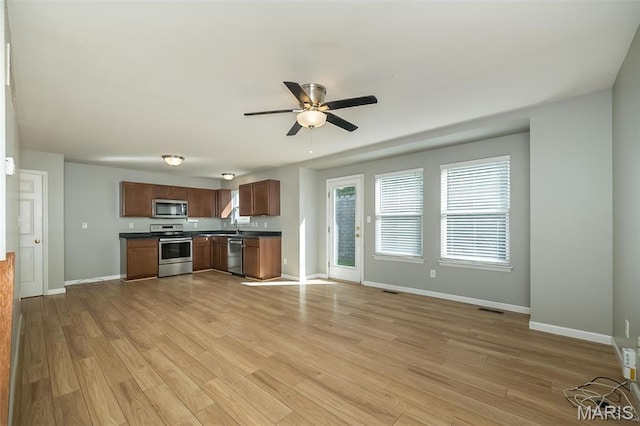 5541 Wavecrest Cir, Saint Charles, MO 63304 - kitchen with stainless steel appliances, dark countertops, baseboards, and light wood finished floors