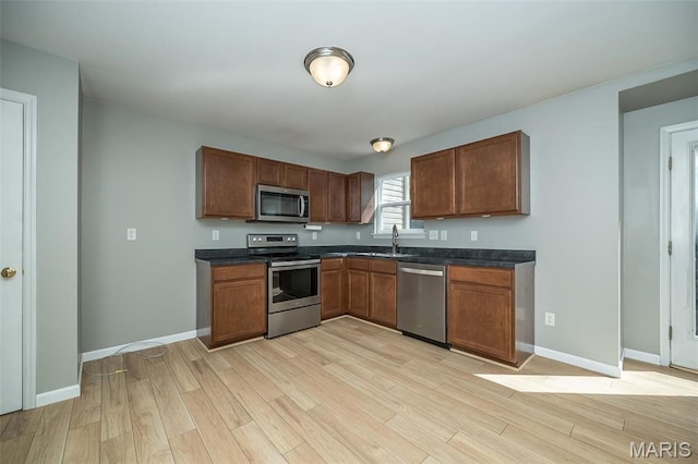 5541 Wavecrest Cir, Saint Charles, MO 63304 - kitchen with stainless steel appliances, dark countertops, light wood-style floors, and baseboards