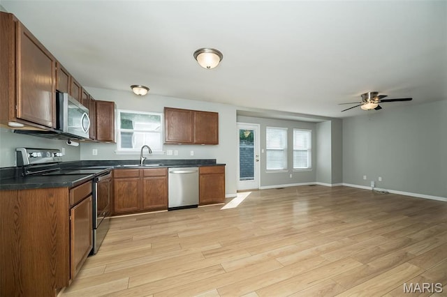 5541 Wavecrest Cir, Saint Charles, MO 63304 - kitchen featuring stainless steel appliances, dark countertops, baseboards, light wood-style flooring, and a ceiling fan