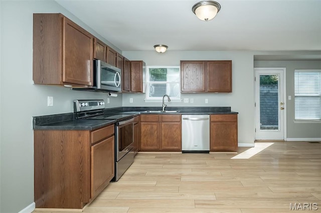 5541 Wavecrest Cir, Saint Charles, MO 63304 - kitchen with appliances with stainless steel finishes, a sink, dark countertops, light wood-style floors, and baseboards