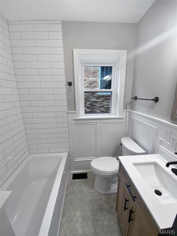 full bath with toilet, vanity, wainscoting, tile patterned floors, and bathing tub / shower combination