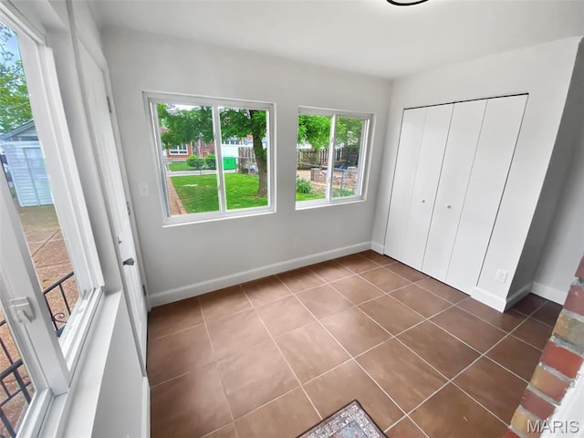 unfurnished bedroom with dark tile patterned flooring, baseboards, and a closet