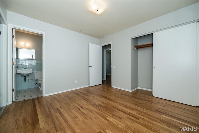 525 Angelus Dr, Florissant, MO 63031 - unfurnished bedroom featuring wood finished floors, ensuite bathroom, a sink, a closet, and baseboards