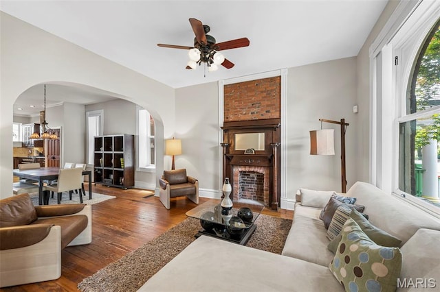 2612 S Compton Ave, Saint Louis, MO 63118 - living room featuring arched walkways, hardwood / wood-style floors, ceiling fan, a chandelier, and a brick fireplace