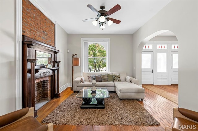 2612 S Compton Ave, Saint Louis, MO 63118 - living area with ceiling fan, wood-type flooring, a brick fireplace, and arched walkways