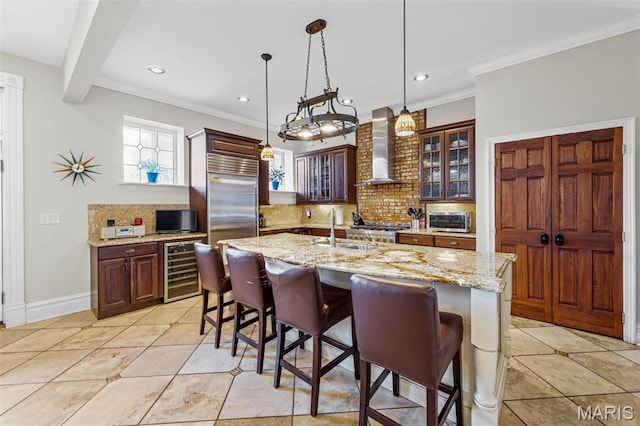 2612 S Compton Ave, Saint Louis, MO 63118 - kitchen featuring wall chimney range hood, beverage cooler, stainless steel built in fridge, tasteful backsplash, and a breakfast bar area