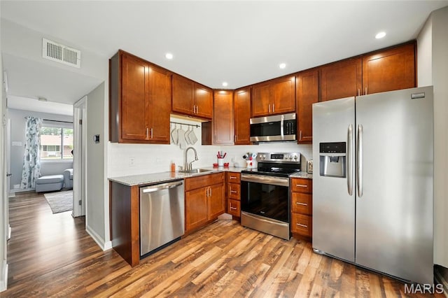 10566 Carroll Wood Way, Saint Louis, MO 63128 - kitchen featuring appliances with stainless steel finishes, a sink, wood finished floors, decorative backsplash, and recessed lighting