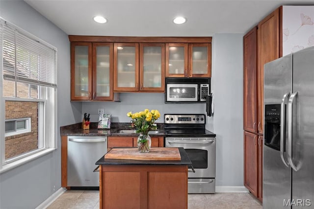 7337 Bruno Ave, Richmond Heights, MO 63117 - kitchen featuring appliances with stainless steel finishes, baseboards, glass insert cabinets, a kitchen island, and brown cabinets
