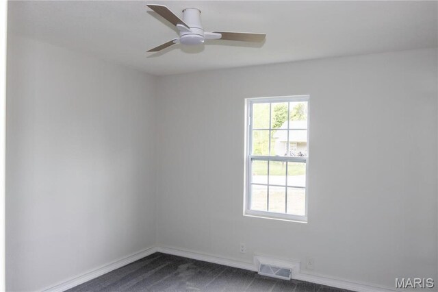 empty room featuring dark carpet, baseboards, and a ceiling fan