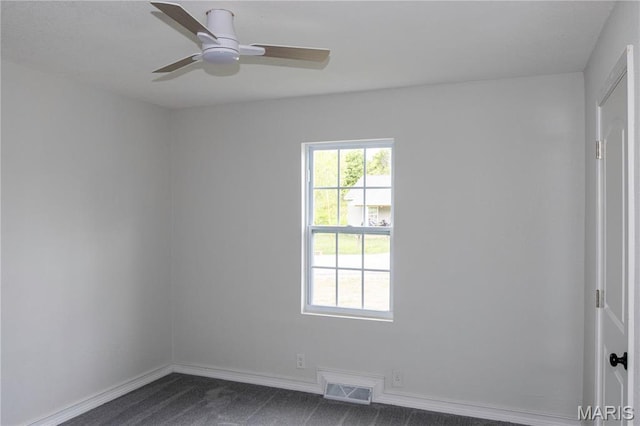 unfurnished room featuring dark carpet, a ceiling fan, and baseboards
