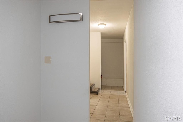 hall featuring light tile patterned floors and baseboards