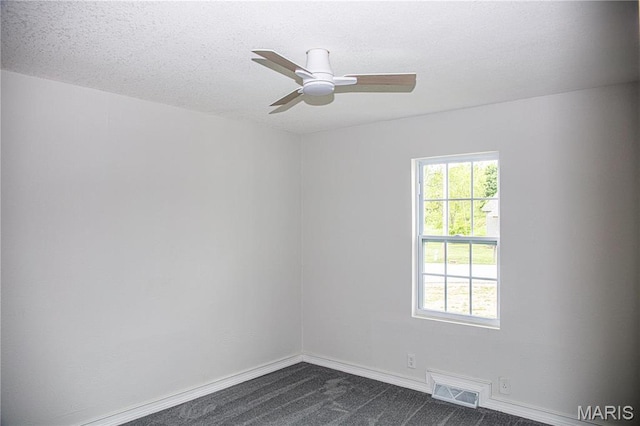 spare room with dark colored carpet, ceiling fan, baseboards, and a textured ceiling