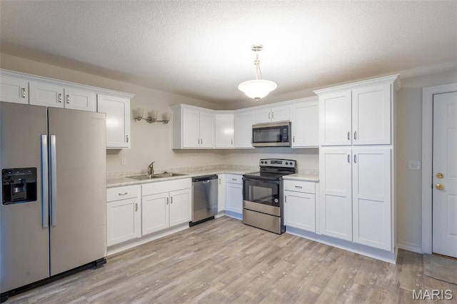 1042 Ash St, Poplar Bluff, MO 63901 - kitchen with appliances with stainless steel finishes, a sink, light countertops, white cabinetry, and a textured ceiling