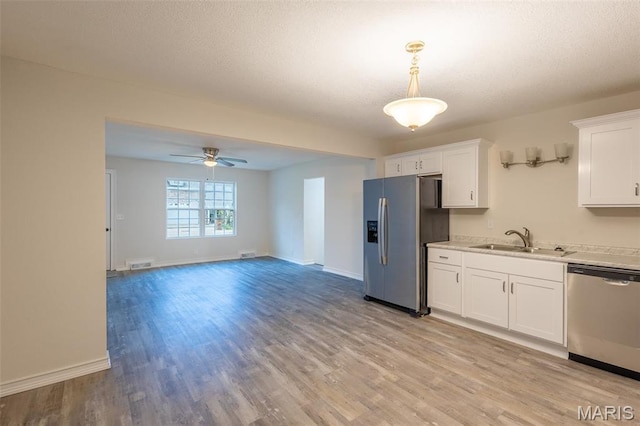 1042 Ash St, Poplar Bluff, MO 63901 - kitchen with appliances with stainless steel finishes, a sink, light wood finished floors, light countertops, and white cabinets