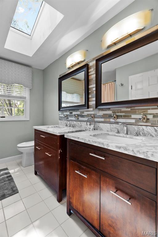 19 Sackston Woods Ln, Saint Louis, MO 63141 - bathroom with a skylight, tile patterned floors, vanity, toilet, and baseboards