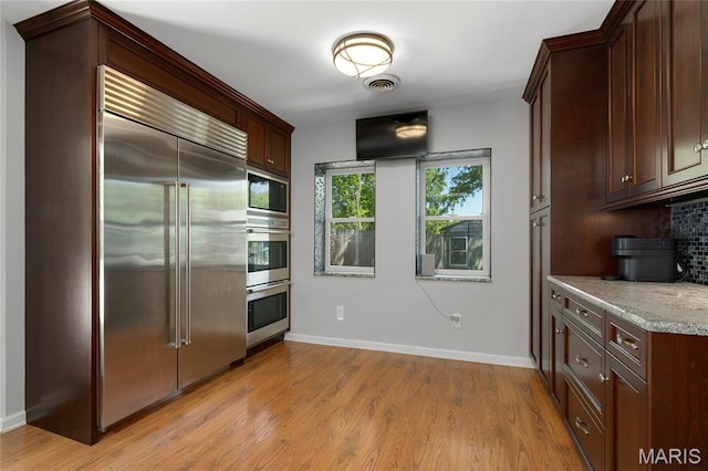 1345 Cheshire Ln, Webster Groves, MO 63119 - kitchen featuring built in appliances, backsplash, light wood finished floors, baseboards, and light stone countertops