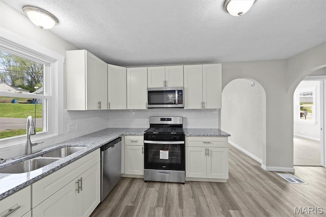 315 Meister St, Collinsville, IL 62234 - kitchen featuring stainless steel appliances, a sink, a textured ceiling, light wood-type flooring, and arched walkways