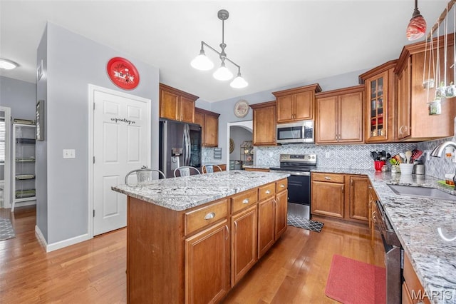 kitchen featuring stainless steel appliances, a sink, brown cabinets, and a center island