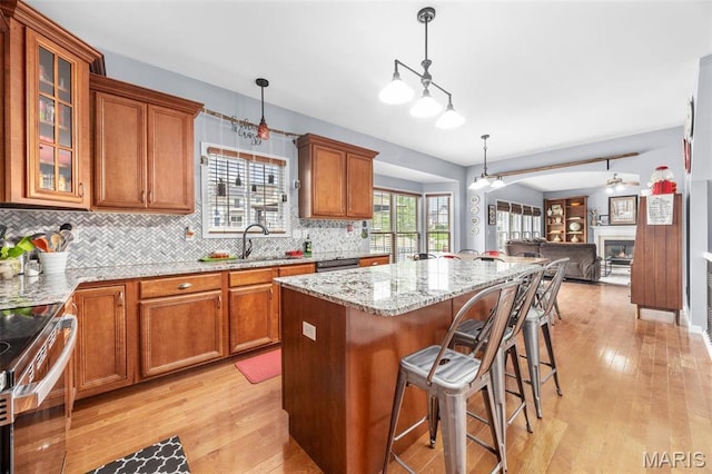 kitchen with open floor plan, brown cabinets, a sink, and light wood-style floors