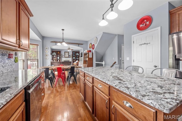 kitchen featuring stainless steel dishwasher, brown cabinets, and light wood finished floors