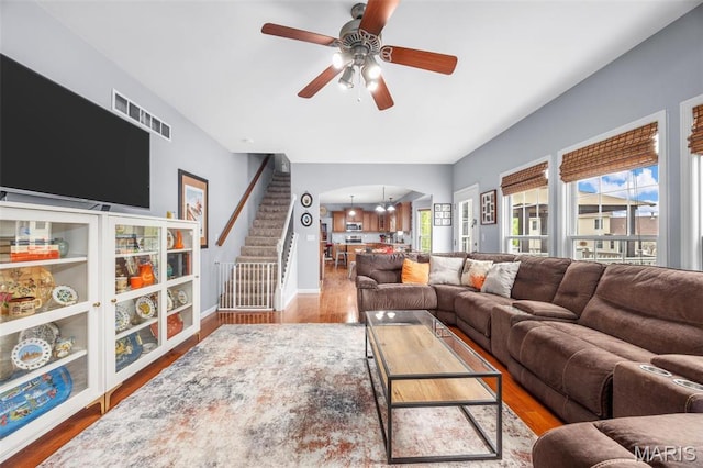 living room featuring a ceiling fan, stairway, wood finished floors, and baseboards